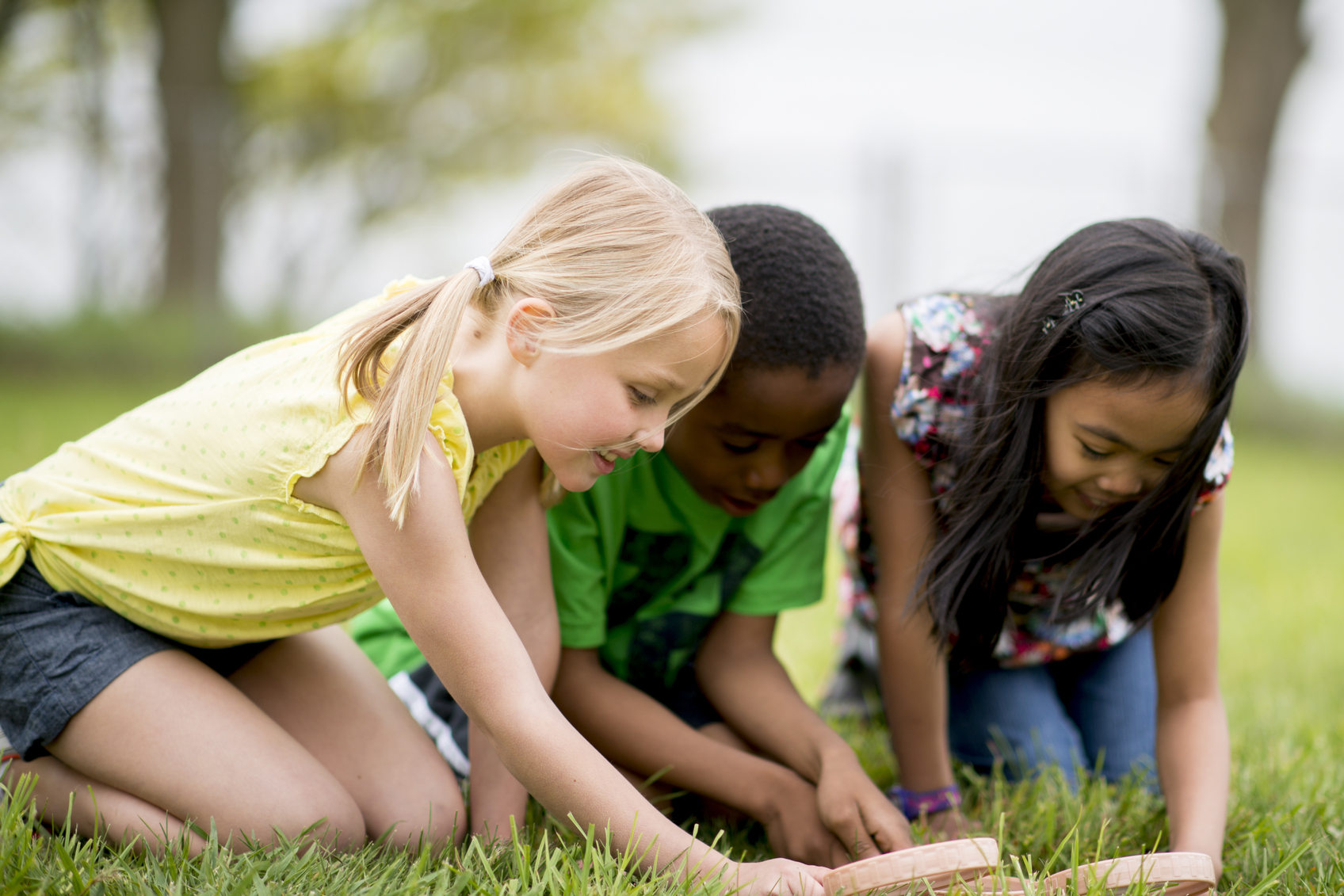 A multi-ethnic group of students looking through a magnifying glass.